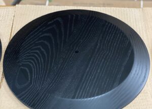 Black-finished ash wood medallion with visible grain and CNC-machined contours.
