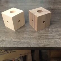 Cube-shaped lighting components made from hard maple with drilled holes for wiring and mounting.