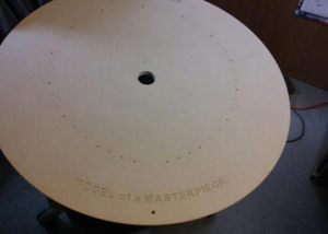 Large MDF base with precision-drilled holes and routed “MODEL of a MASTERPIECE” inscription.