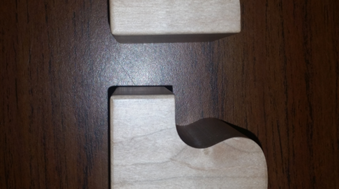 Two interlocking puzzle-shaped lamp base halves CNC machined from soft maple wood.