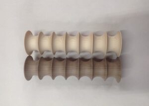 Fluted lighting components made from walnut and hard maple, shown in symmetrical rows on a white surface.