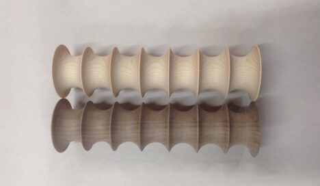 Fluted lighting components made from walnut and hard maple, shown in symmetrical rows on a white surface.